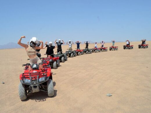 Group of people on red quad bikes in the sunny desert during a morning quad bike tour in Hurghada.