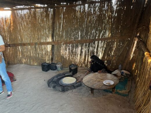 A Bedouin woman bakes traditional flatbread over an open fire in a reed hut for safari tourists. Hurghada Fun Trips
