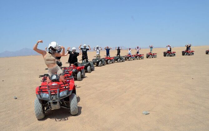 Gruppe von Menschen auf roten Quad-Bikes in der sonnigen Wüste bei einer Quad-Bike-Morgen-Tour in Hurghada.