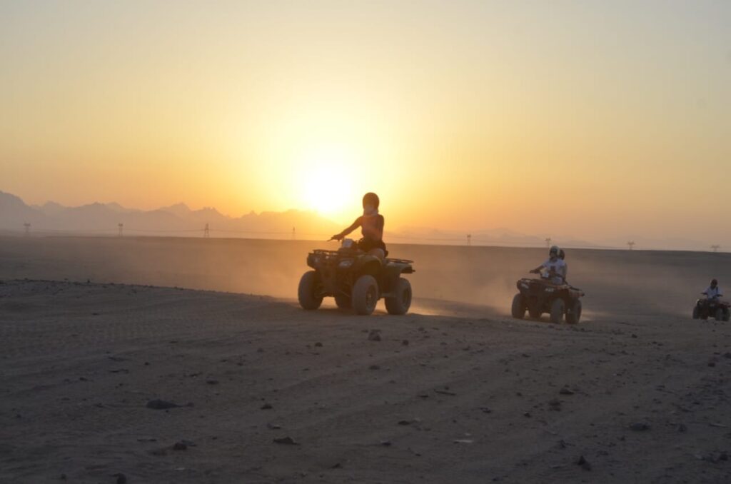 Tourists riding quad bikes through the desert at sunset in Hurghada. Quad bike sunset trip