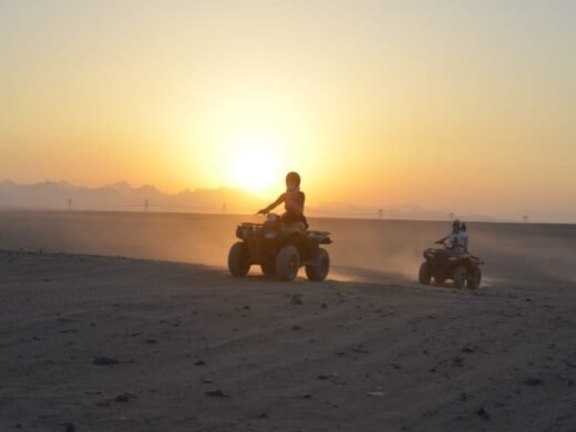 Tourists riding quad bikes through the desert at sunset in Hurghada. Quad bike sunset trip