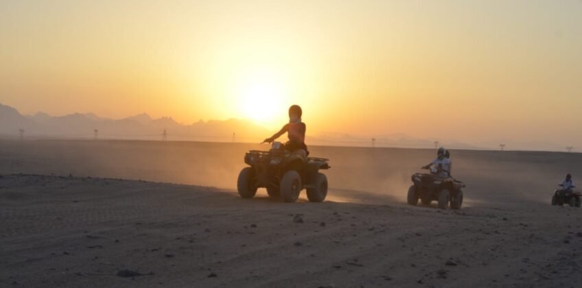 Tourists riding quad bikes through the desert at sunset in Hurghada. Quad bike sunset trip