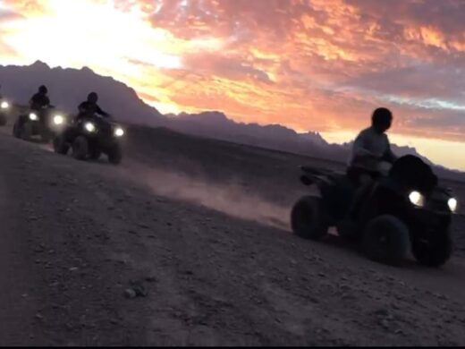 Touristen fahren mit Quads durch die Wüste bei Sonnenuntergang in Hurghada. Quad-Ausflug bei Sonnenuntergang