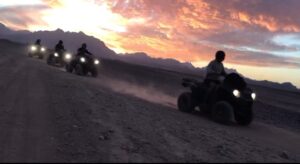 Tourists riding quad bikes through the desert at sunset in Hurghada. Quad bike sunset trip