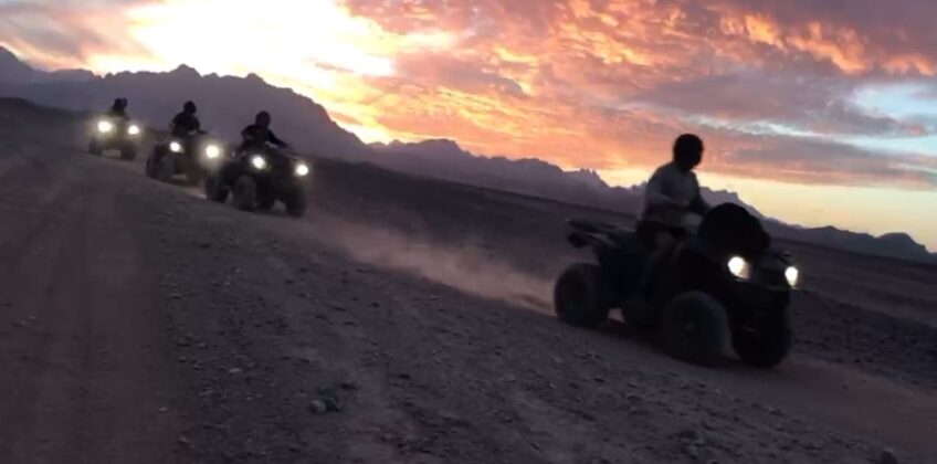 Tourists riding quad bikes through the desert at sunset in Hurghada. Quad bike sunset trip