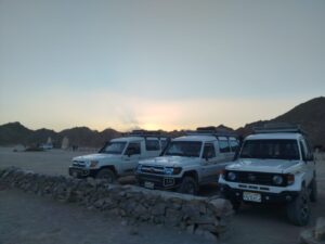 Trzy białe samochody Toyota Land Cruiser zaparkowane na pustyni przed wielką wycieczką safari w Hurghadzie