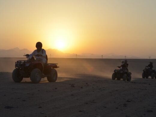 Tourists riding quad bikes through the desert at sunset in Hurghada. Quad bike sunset trip