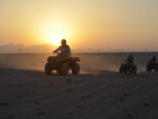 Tourists riding quad bikes through the desert at sunset in Hurghada. Quad bike sunset trip