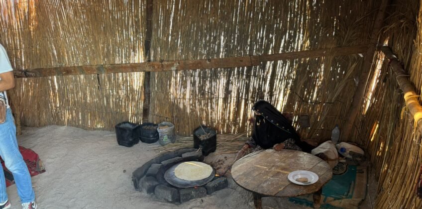 A Bedouin woman bakes traditional flatbread over an open fire in a reed hut for safari tourists. Hurghada Fun Trips