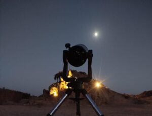 Profesionální dalekohled na stativu připravený k pozorování hvězd v egyptské poušti pod měsíčním nebem, výlet Stargazing Safari