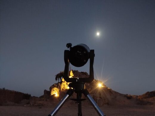 Profesjonalny teleskop na statywie ustawiony do obserwacji gwiazd na egipskiej pustyni pod księżycowym niebem, wycieczka Stargazing Safari