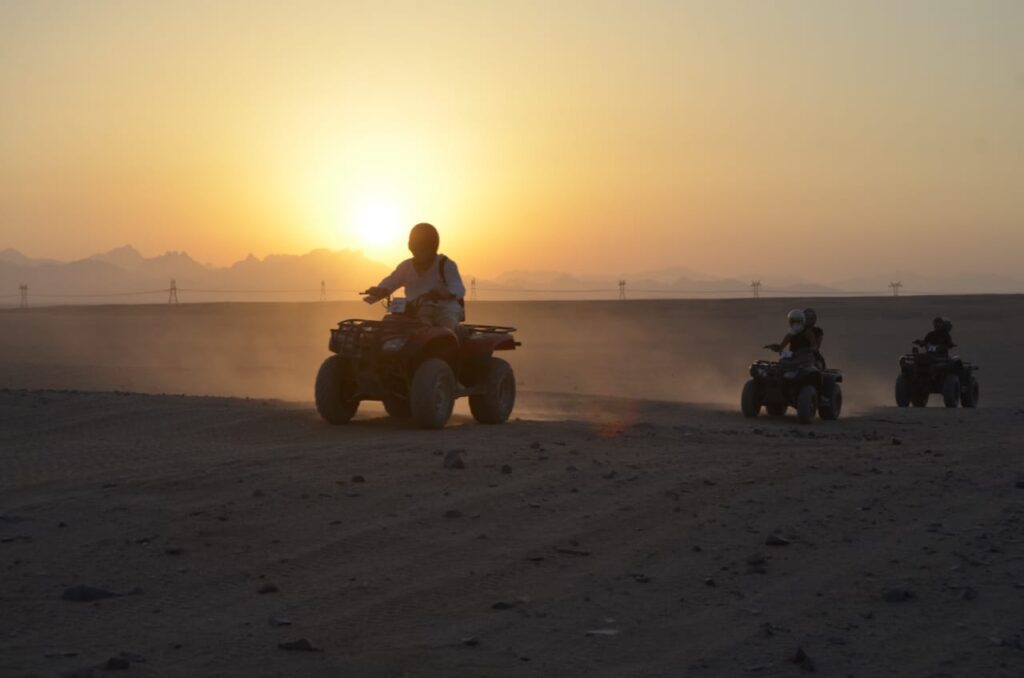 Tourists riding quad bikes through the desert at sunset in Hurghada. Quad bike sunset trip